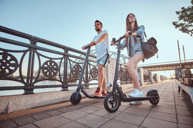 Genç çift, elektro scooterların keyfini çıkarıyor.