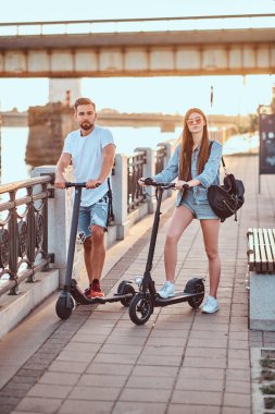 Genç çift, elektro scooterların keyfini çıkarıyor.