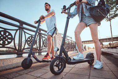 Genç çift, elektro scooterların keyfini çıkarıyor.