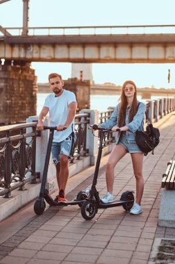 Genç çift, elektro scooterların keyfini çıkarıyor.