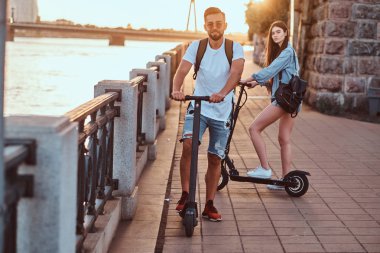 Genç çift, elektro scooterların keyfini çıkarıyor.