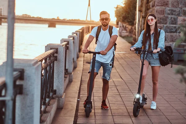 Deux amis profitent de la journée d'été avec leurs scooters électriques — Photo