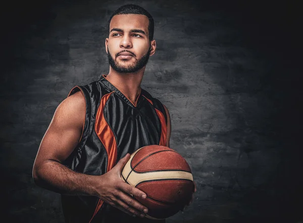 Jugador de baloncesto sostiene una pelota sobre fondo gris . — Foto de Stock