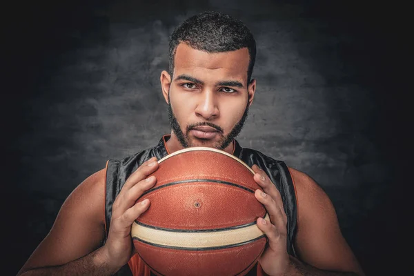 Een zwarte man houdt een basket ball. — Stockfoto