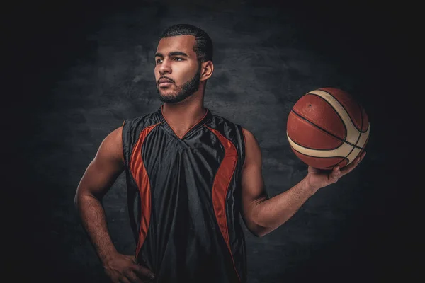 Jugador de baloncesto sostiene una pelota sobre fondo gris . — Foto de Stock