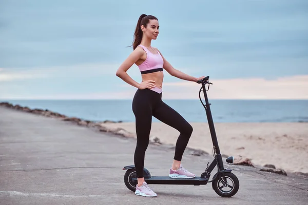 Mujer bonita está conduciendo su scooter a orillas del mar —  Fotos de Stock