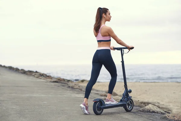 Mooie vrouw rijdt haar scooter door de kust — Stockfoto