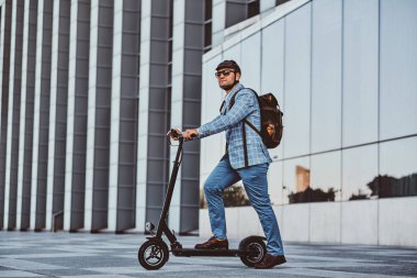 Adam büyük cam binanın yakınında onun yeni elektro scooter sürüyor