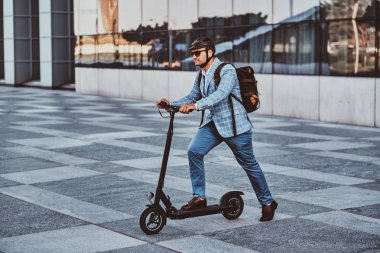 Adam büyük cam binanın yakınında onun yeni elektro scooter sürüyor