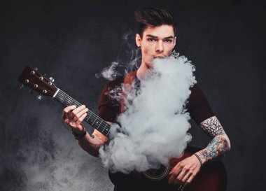 Çekici adam akustik gitar çalıyor ve sigara içiyor