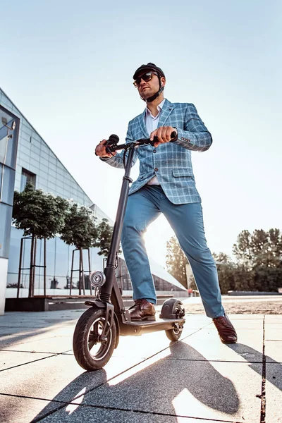 Чоловік керує своїм новим електро скутером біля великої скляної будівлі — стокове фото