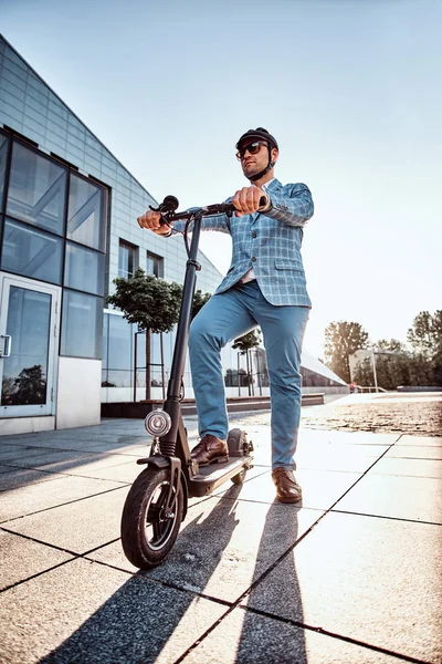 Homem está dirigindo sua nova scooter electro perto de um grande edifício de vidro — Fotografia de Stock
