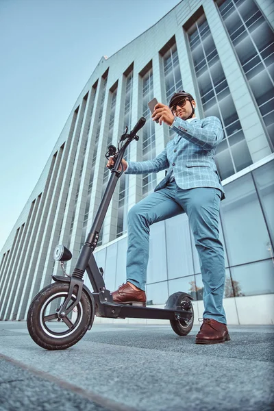 Man rijdt zijn nieuwe electro scooter in de buurt van grote glazen gebouw — Stockfoto