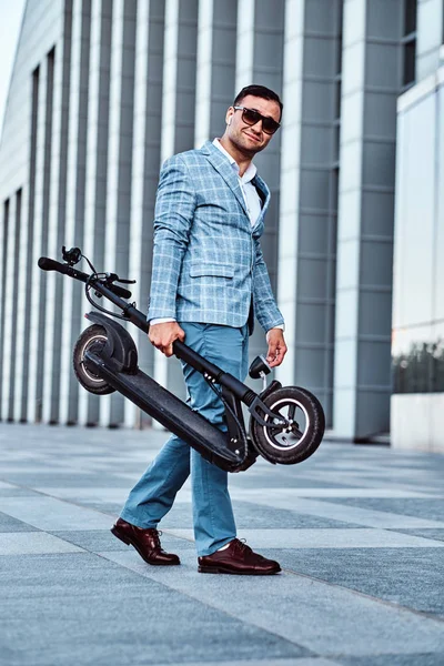 Elegante hombre está sosteniendo electro scooter —  Fotos de Stock