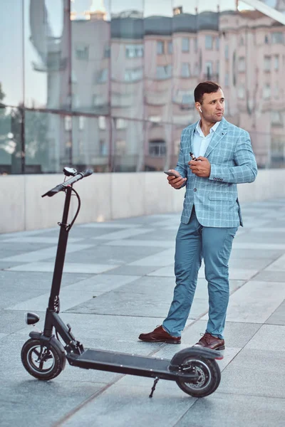 Handsome man is standing near his electro scooter — Stock Photo, Image