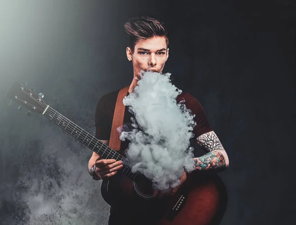 Attractive guy is playing acoustic guitar and smoking — Stock Photo, Image