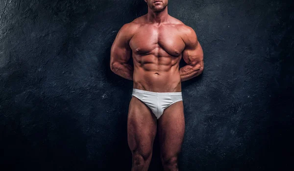 Hombre con hermoso cuerpo muscular está posando sobre fondo oscuro —  Fotos de Stock