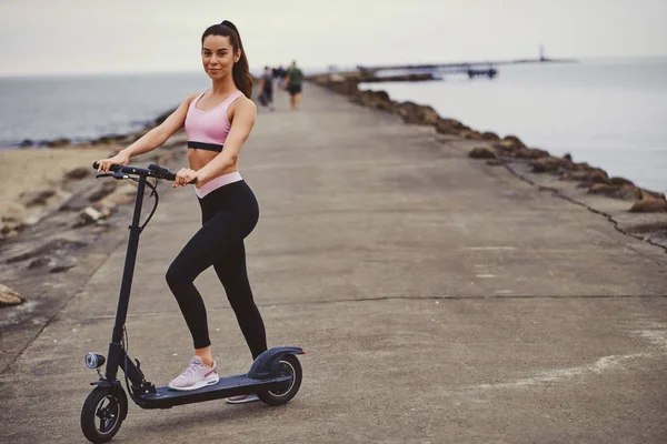 Mujer bonita está conduciendo su scooter a orillas del mar — Foto de Stock