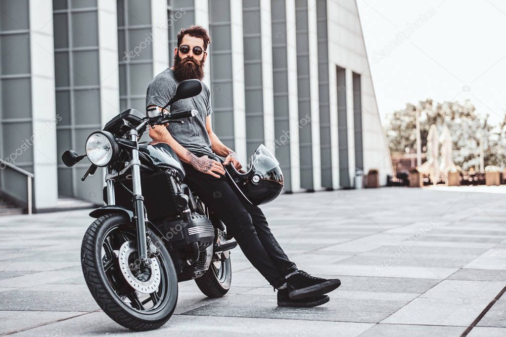 Portrait of bearded biker chilling with his motorbike