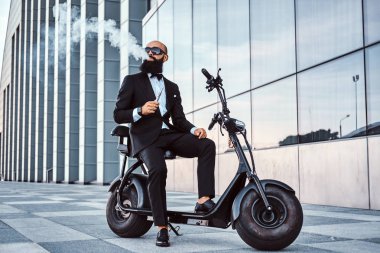 Zarif işadamı elektro bisiklet üzerinde otururken sigara içiyor