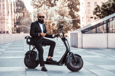 Modern adam yeni elektro scooter'ının üzerinde oturuyor.