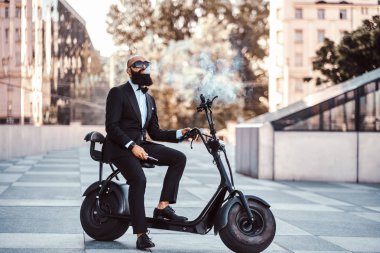 Modern adam yeni elektro scooter'ının üzerinde oturuyor.