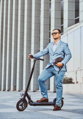 Adam büyük cam binanın yakınında onun yeni elektro scooter sürüyor