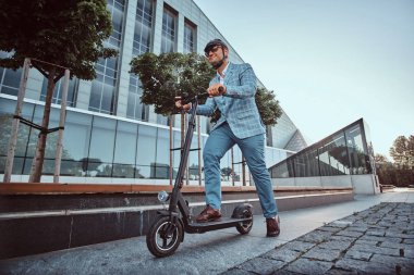 Adam büyük cam binanın yakınında onun yeni elektro scooter sürüyor