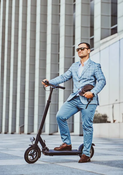 L'homme conduit son nouveau scooter électrique près du grand bâtiment en verre — Photo