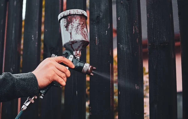 Flitig arbetar tillämpar färg på stängslet med airbrush — Stockfoto
