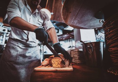 Mutfak işçisi öğle yemeği için ekmek dilimleme