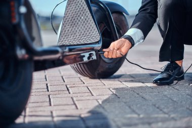 Adam yeni elektro scooter'ını şarj ediyor.