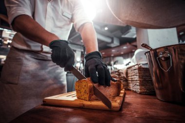 Mutfak işçisi öğle yemeği için ekmek dilimleme