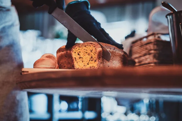 Mutfak işçisi öğle yemeği için ekmek dilimleme