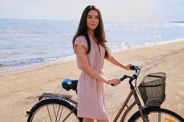 Retrato de bela morena com sua bicicleta à beira-mar — Fotografia de Stock