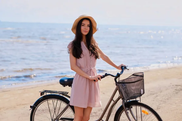 Portret van mooie brunette met haar fiets aan de kust — Stockfoto