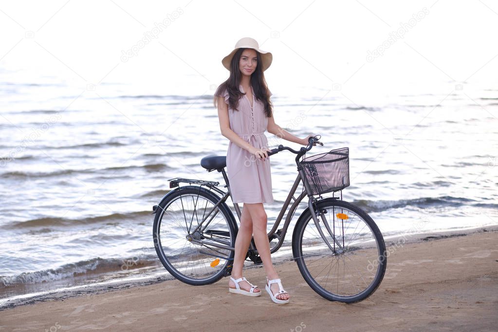 Portrait of beautiful brunette with her bike at the seaside