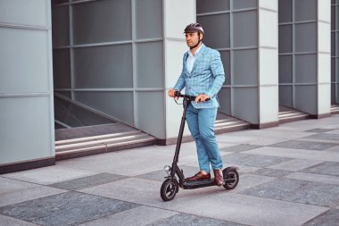 Yakışıklı adam ofis binasıyakınında onun scooter biniyor