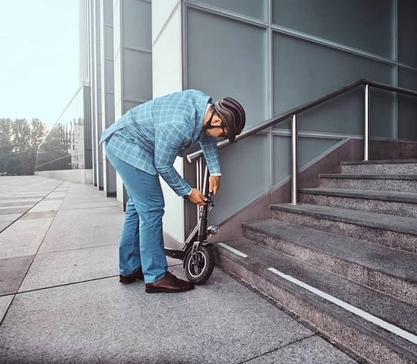 Mann parkt seinen Elektroroller und legt Kettenschloss drauf — Stockfoto