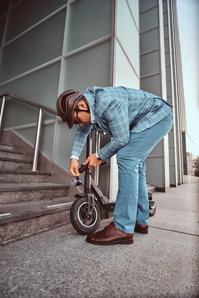 El hombre está aparcando su electro scooter y cerradura de cadena ut en él — Foto de Stock