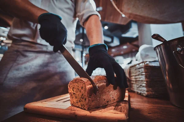 Kuchyňský pracovník na oběd krájí chleba — Stock fotografie