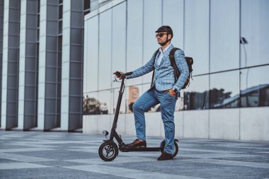 Adam büyük cam binanın yakınında onun yeni elektro scooter sürüyor