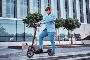 Yakışıklı adam ofis binasıyakınında onun scooter biniyor