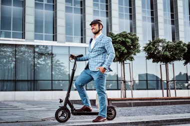Yakışıklı adam ofis binasıyakınında onun scooter biniyor