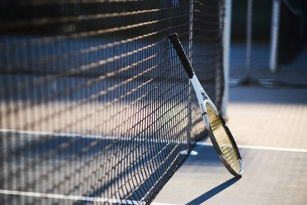 Racchetta da tennis è in piedi vicino alla rete da tennis — Foto Stock