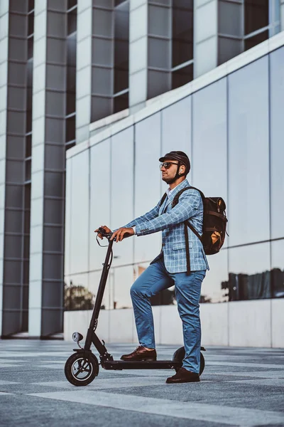 Man rijdt zijn nieuwe electro scooter in de buurt van grote glazen gebouw — Stockfoto