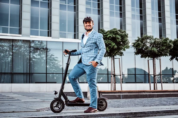 Hombre guapo está montando su scooter cerca del edificio de oficinas —  Fotos de Stock