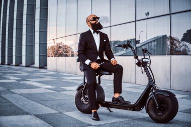 Zarif işadamı elektro bisiklet üzerinde otururken sigara içiyor