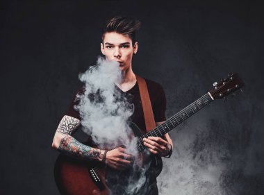 Çekici adam akustik gitar çalıyor ve sigara içiyor