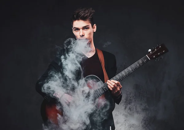 Attrayant gars joue de la guitare acoustique et de fumer — Photo